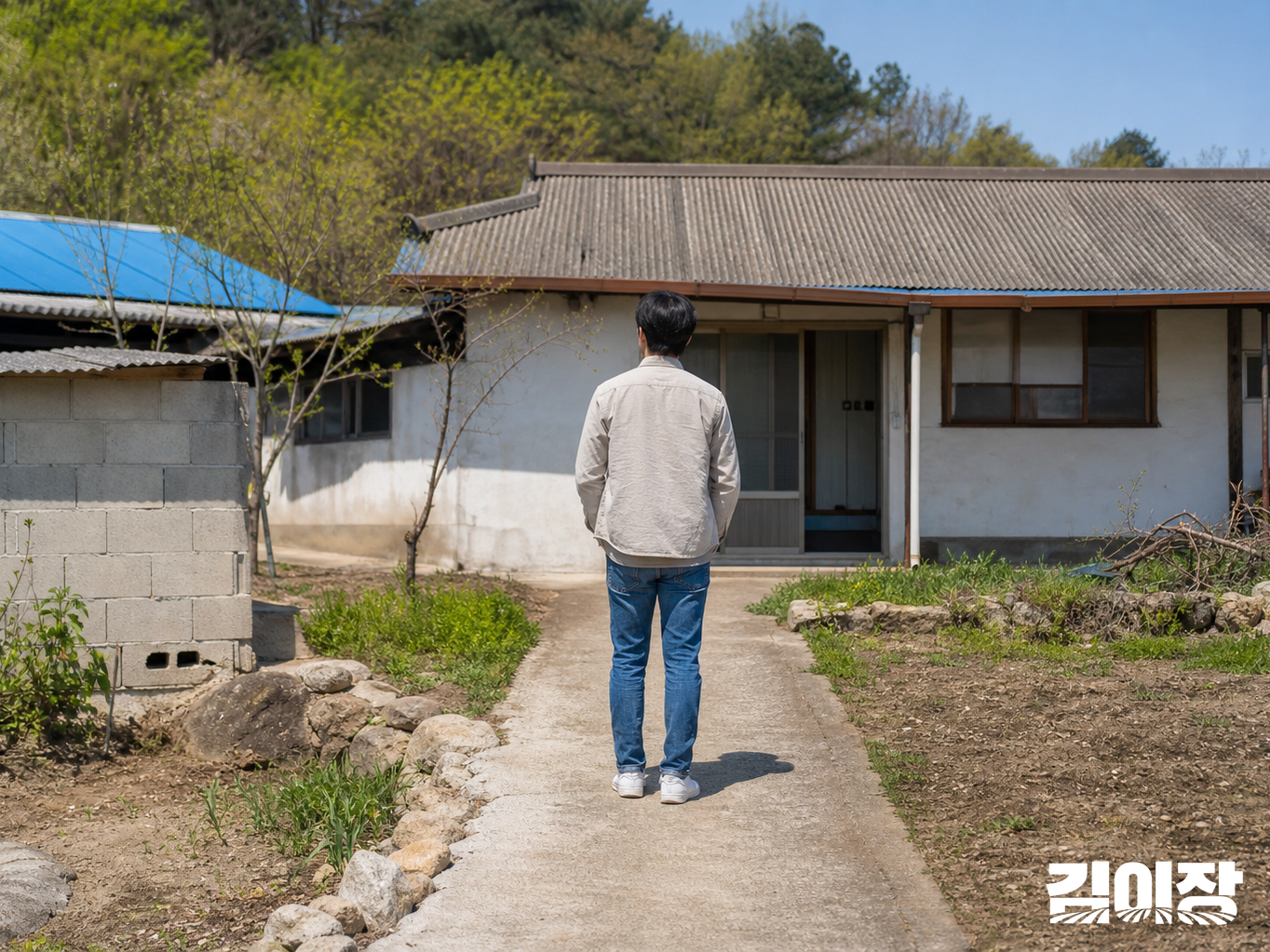 작은 농촌 건물 입구 앞에서 보행로와 출입 동선을 살피는 평상복 차림 성인의 뒷모습